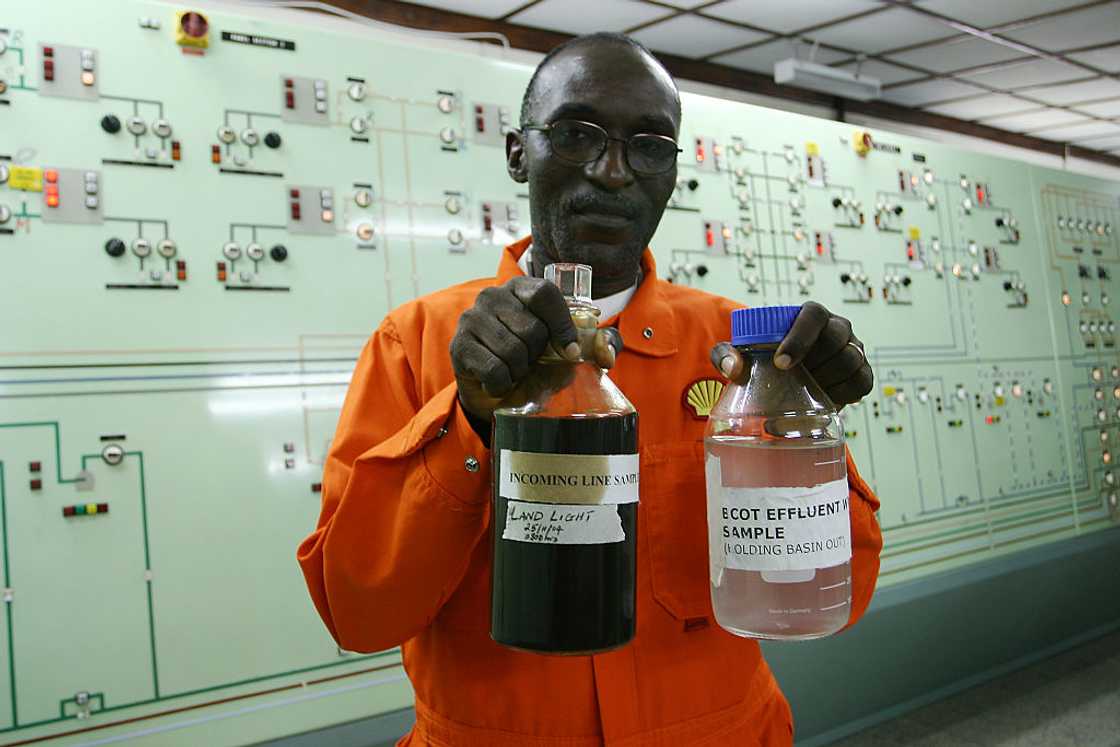 A shell worker holding two bottles with chemicals.