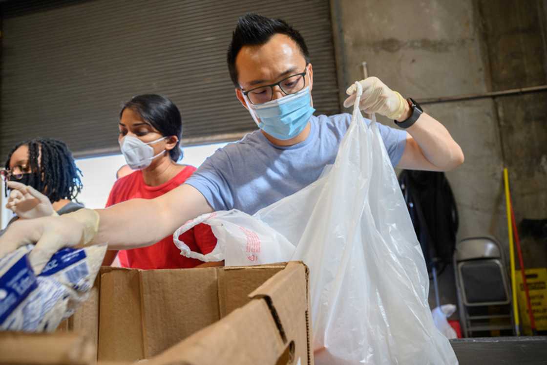 Tony Xu wears a face mask and gloves while packing groceries