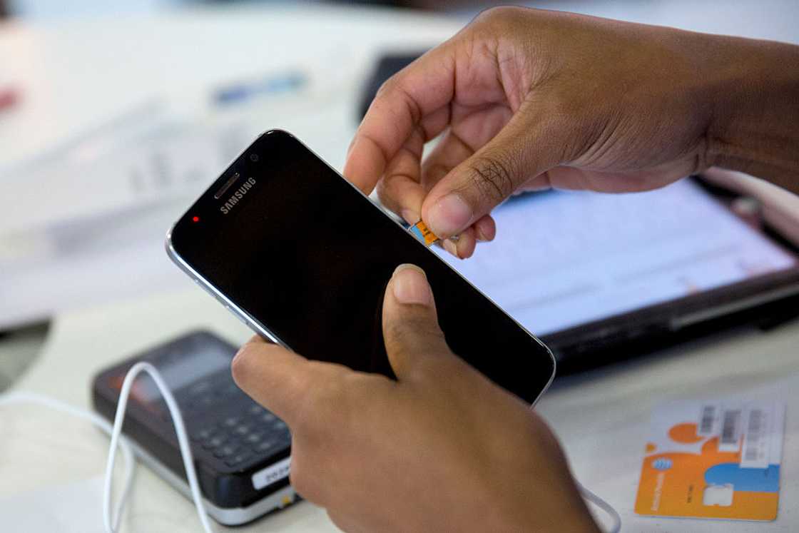 A person inserting a SIM card into a phone.