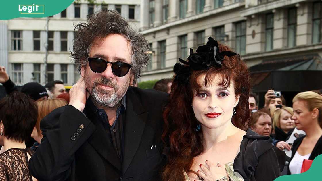 A man with his hand on his neck and a woman with curly hair pose together outdoors in sunglasses. A man with his hand on his neck and a woman with curly hair pose together outdoors in sunglasses.