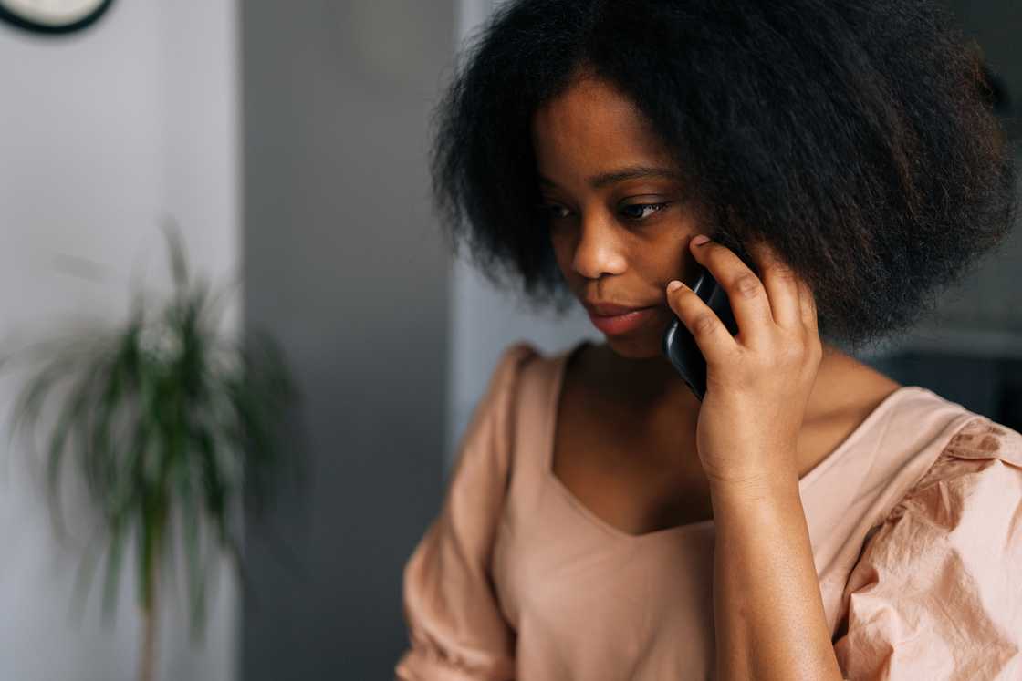 A young woman talking on smartphone at home.