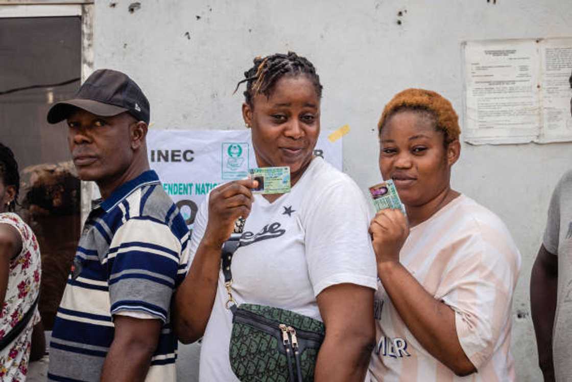 Voters show their voters cards while queueing to cast the ballots at a polling station in Agege, Lagos. Voters show their voters cards while queueing to cast the ballots at a polling station in Agege, Lagos.