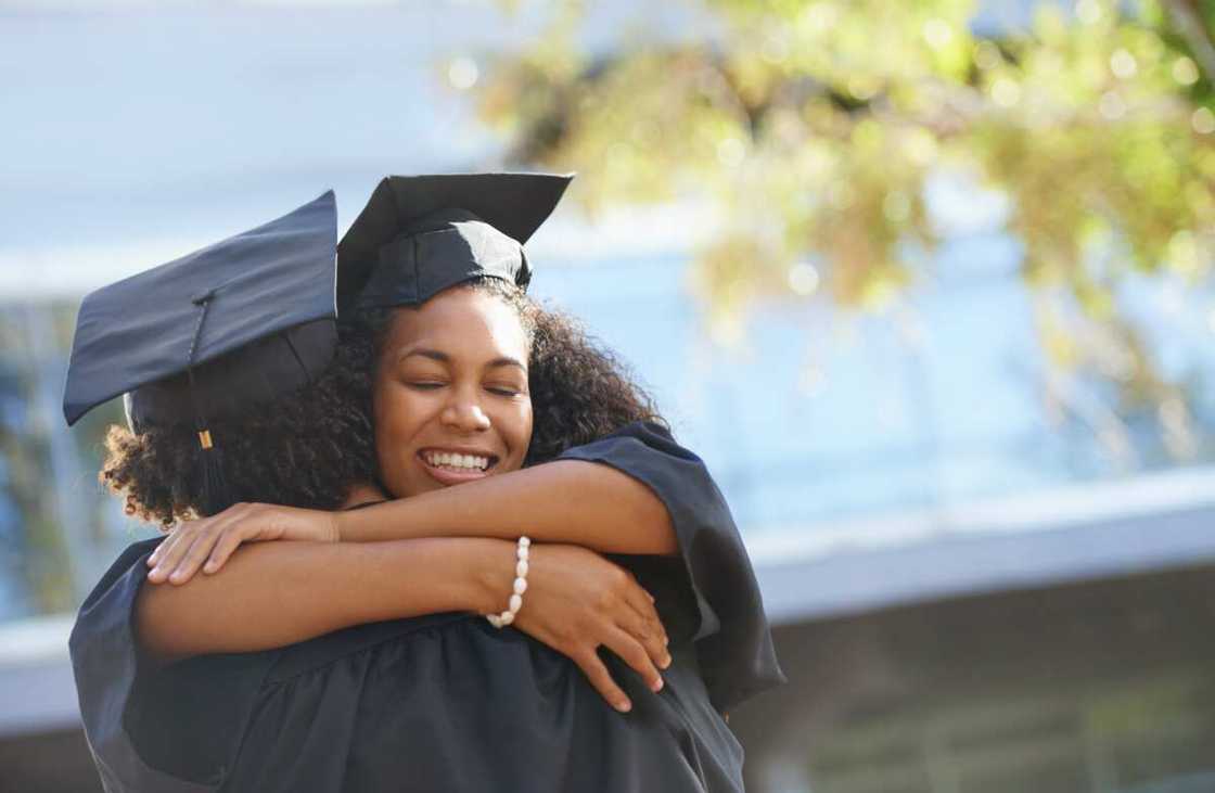 Happy students hugging on graduation day