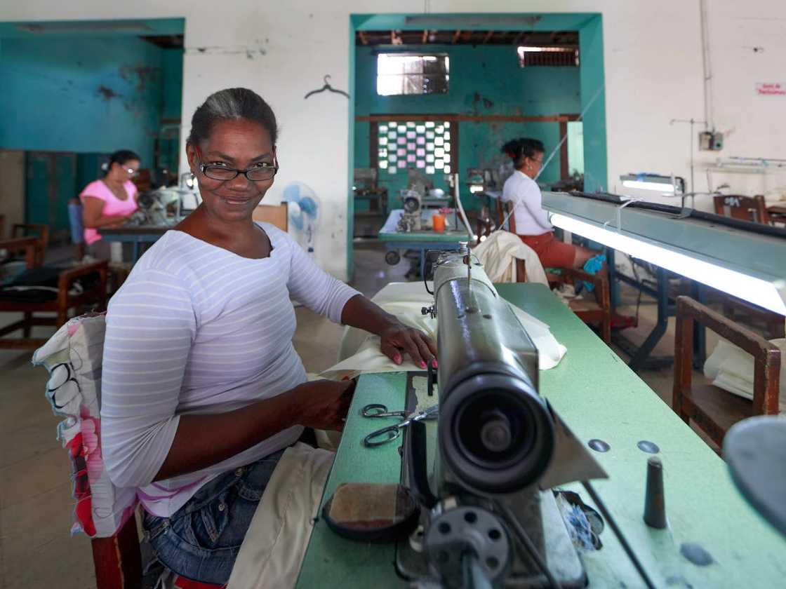 A group of women share sewing machines in a workshop.