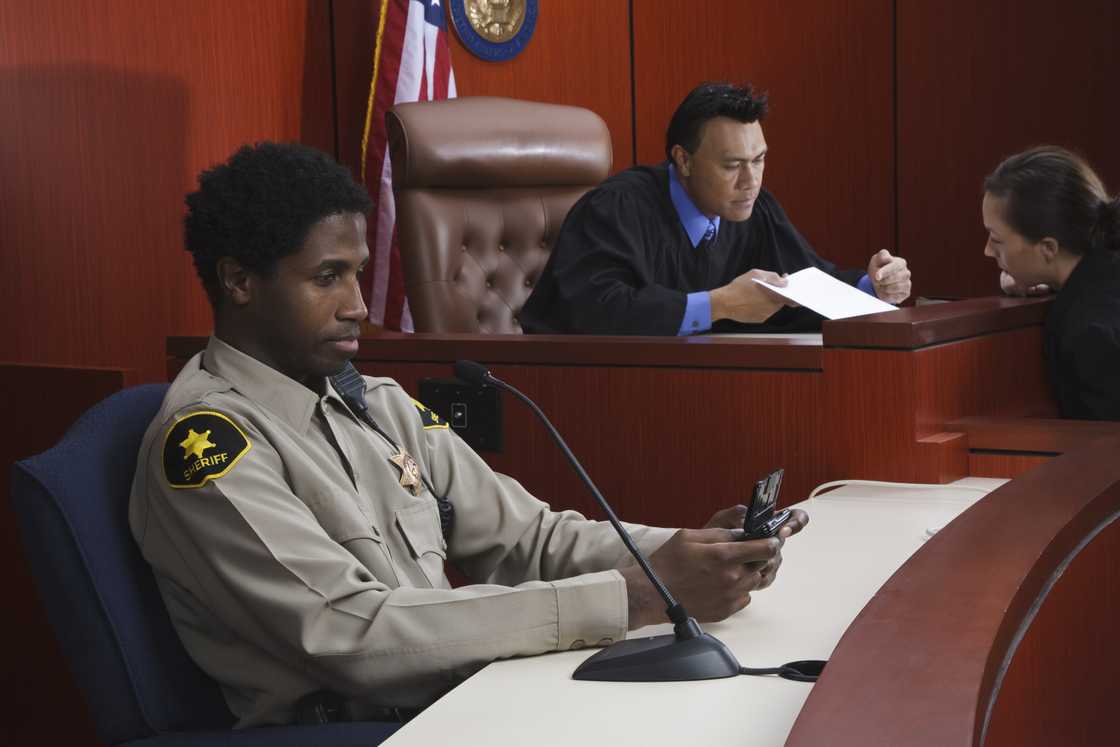 A security officer seated a desk in a court room A security officer seated a desk in a court room