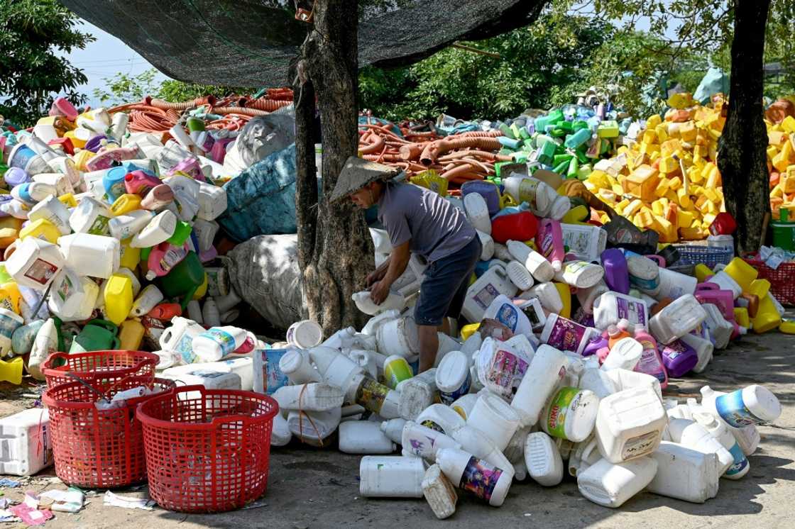 A worker handling plastic bottles before they can be melted into tiny pellets for reuse A worker handling plastic bottles before they can be melted into tiny pellets for reuse