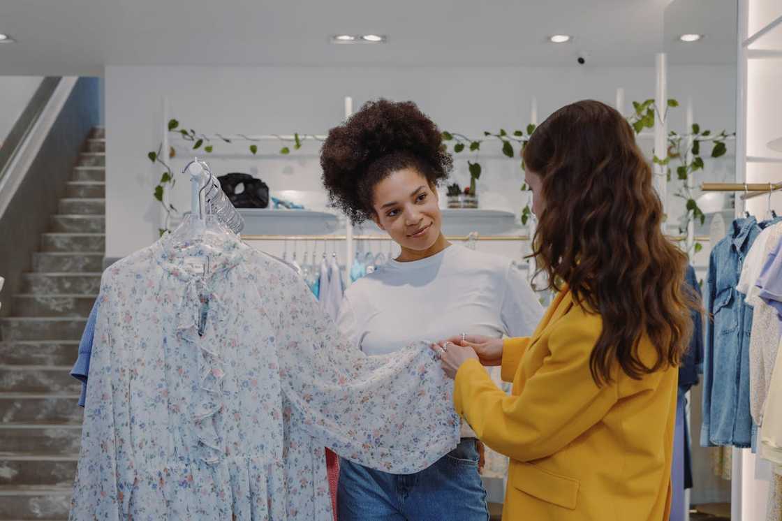 A shop assistant shows a floral blouse to a customer in a boutique. A shop assistant shows a floral blouse to a customer in a boutique.