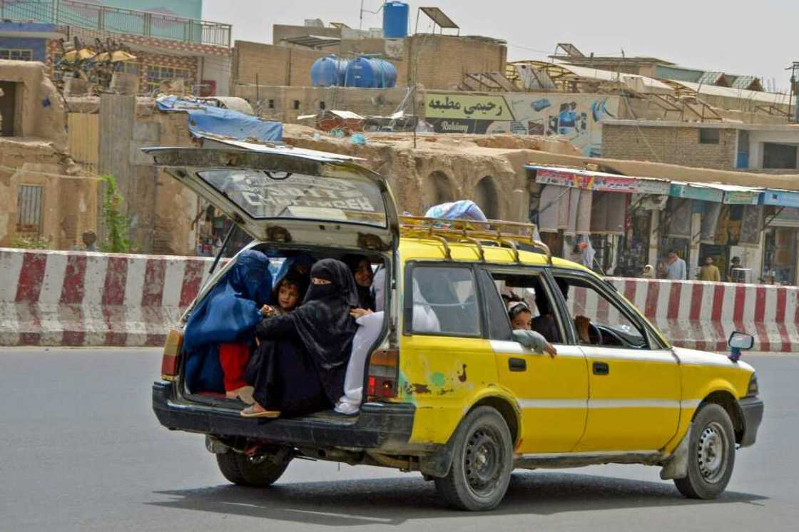 Afghan women and children commute in the back of a taxi in Kandahar