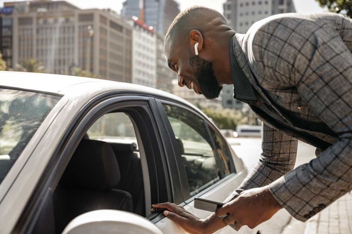 A man talking to a driver through a car window A man talking to a driver through a car window