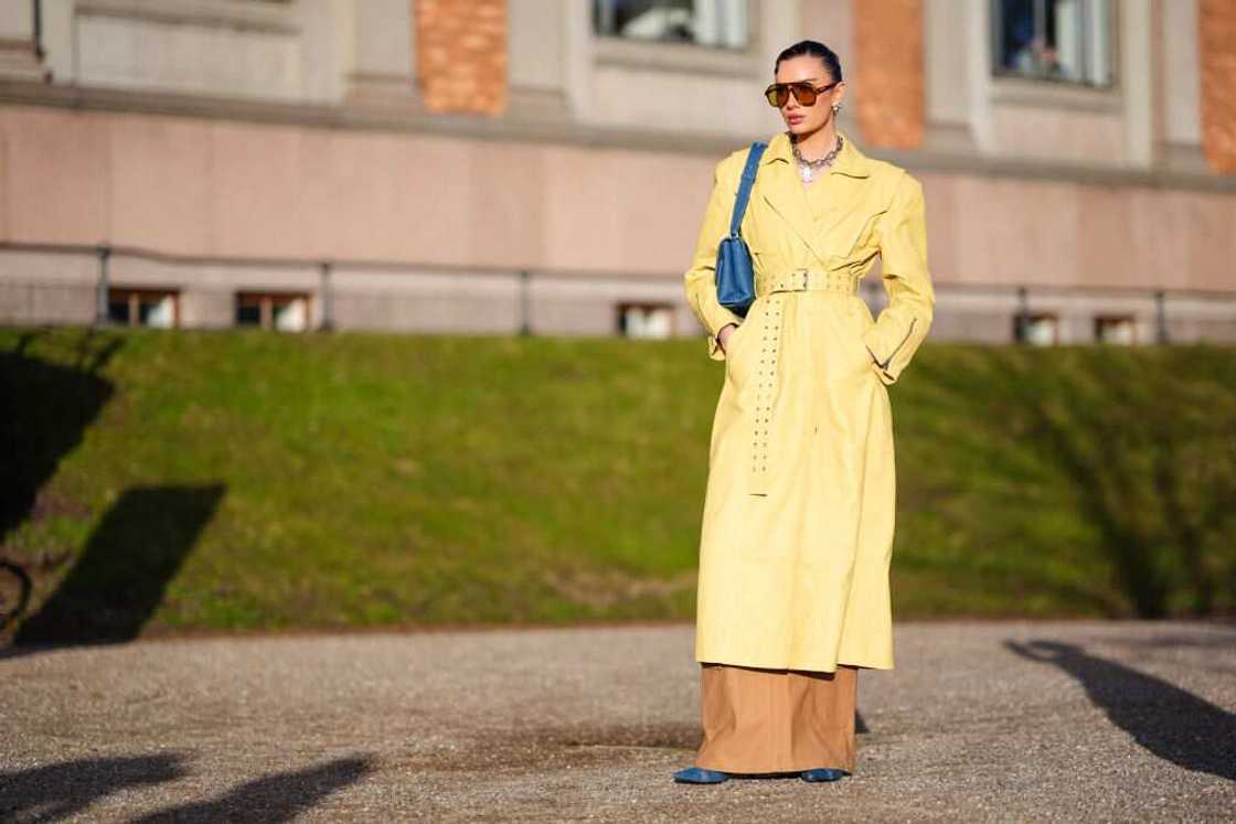 A lady donning a long yellow coat. A lady donning a long yellow coat.