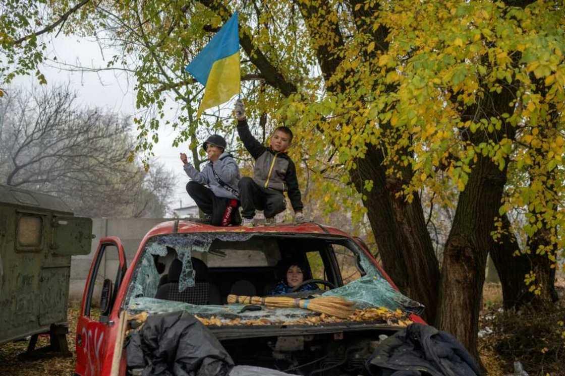 A young boy waves a Ukrainian flag from a destroyed car at a former Russian checkpoint at the entrance to Kherson A young boy waves a Ukrainian flag from a destroyed car at a former Russian checkpoint at the entrance to Kherson