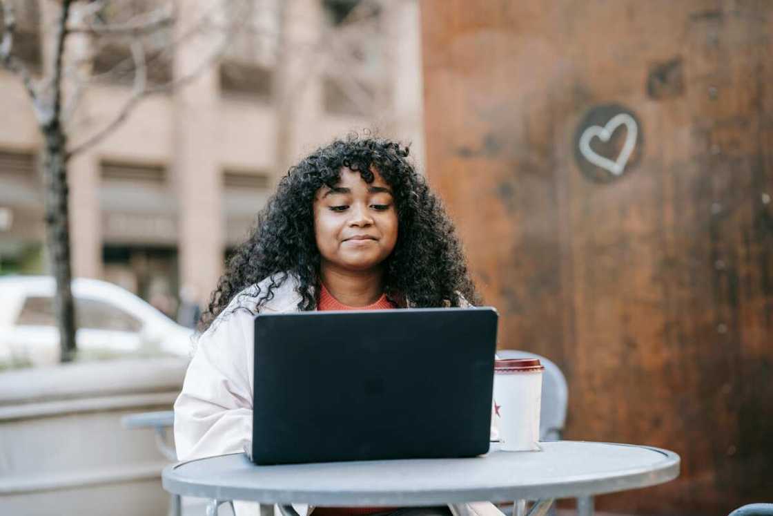 A woman is using a laptop in a street cafe