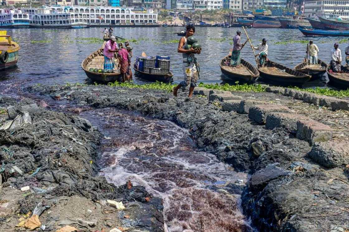 Industrial waste enters the Buriganga River as boatmen wait for passengers in Karanigonj