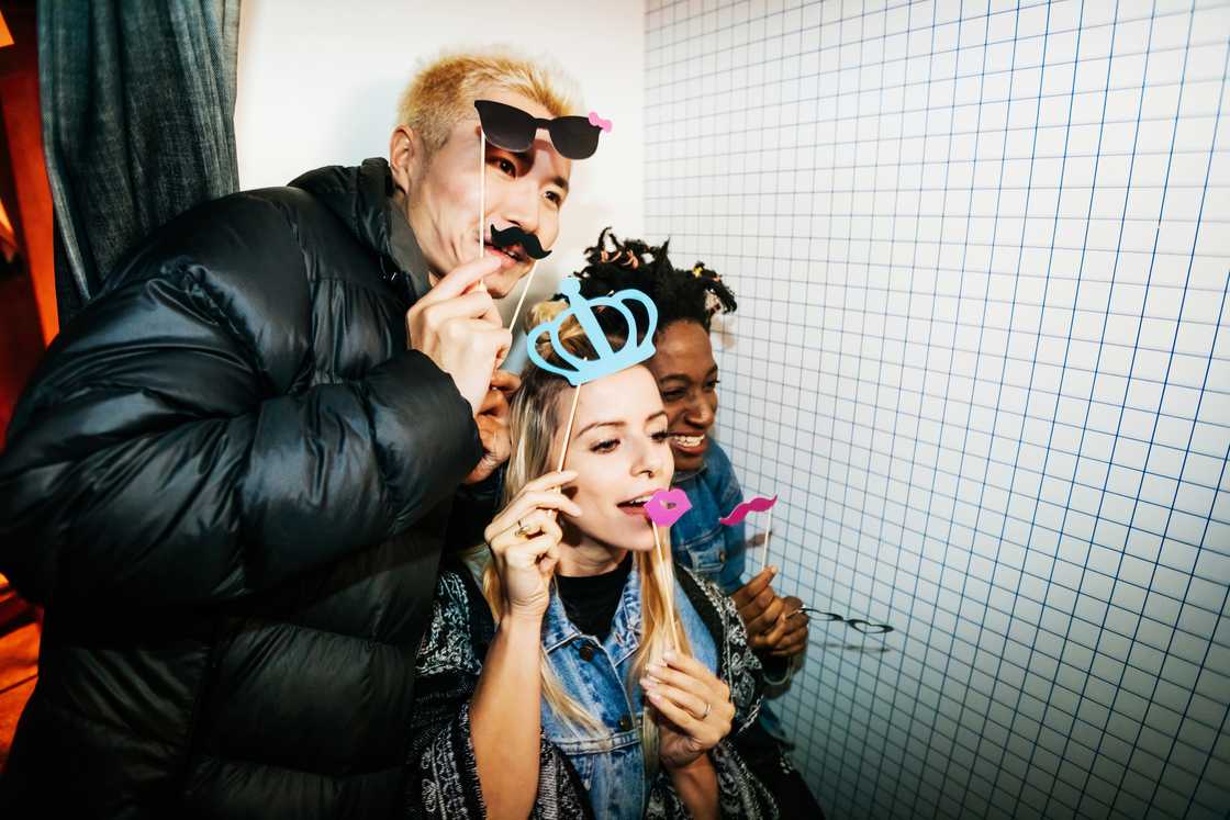 A group of co-workers taking silly pictures with accessories in a photo booth