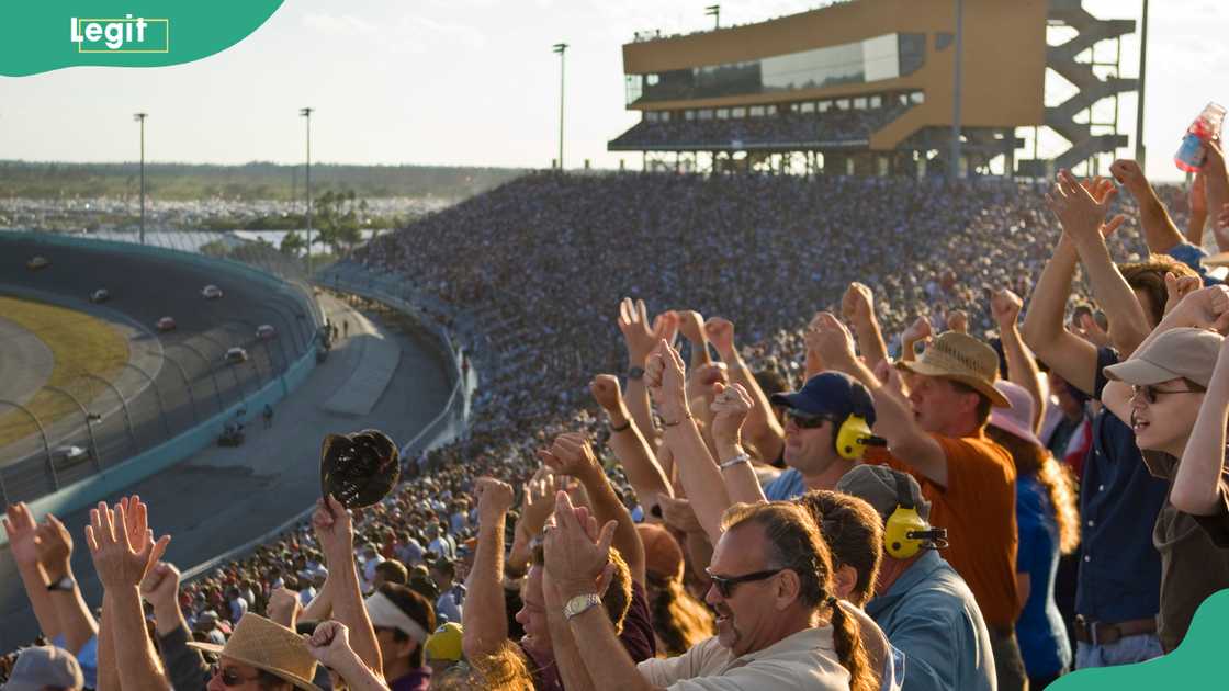 Crowd in stadium watching stock car racing, cheering Crowd in stadium watching stock car racing, cheering