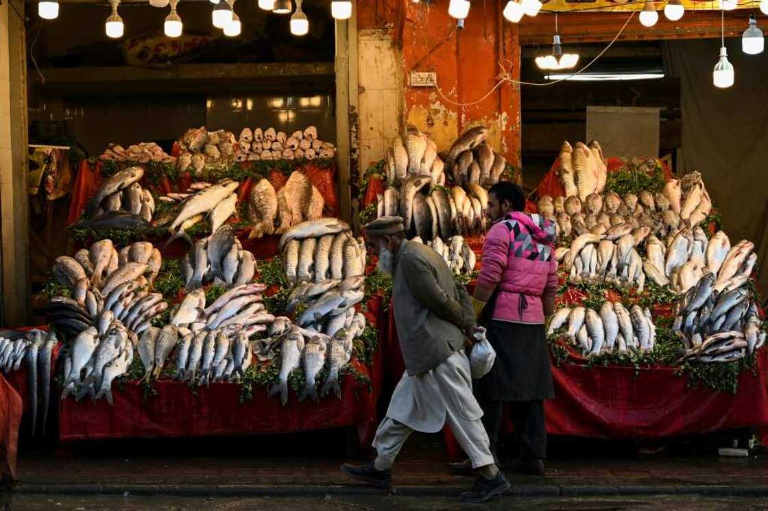 A man walks past a fish market in Rawalpindi. Pakistan's economy is in the doldrums, with soaring inflation, a weak rupee, and dwindling forex reserves