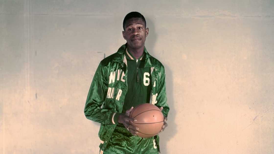 Bill Russell holds a basketball in a University of San Francisco kit.