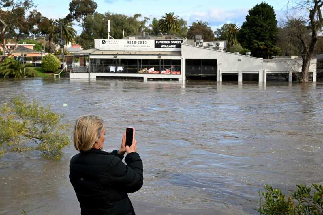 A woman films a flooded area in the Maribyrnong suburb of Melbourne on Friday A woman films a flooded area in the Maribyrnong suburb of Melbourne on Friday
