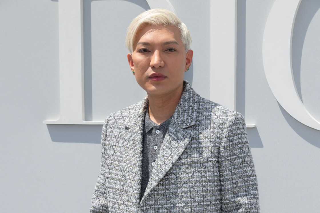 Bryanboy poses in a dark grey T-shirt and chekered blazer at Paris Fashion Week