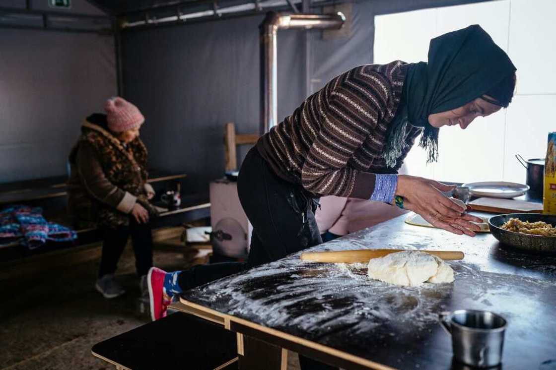 A resident of Borodianka near Kyiv cooks in a tent where she can keep warm after her home was destroyed