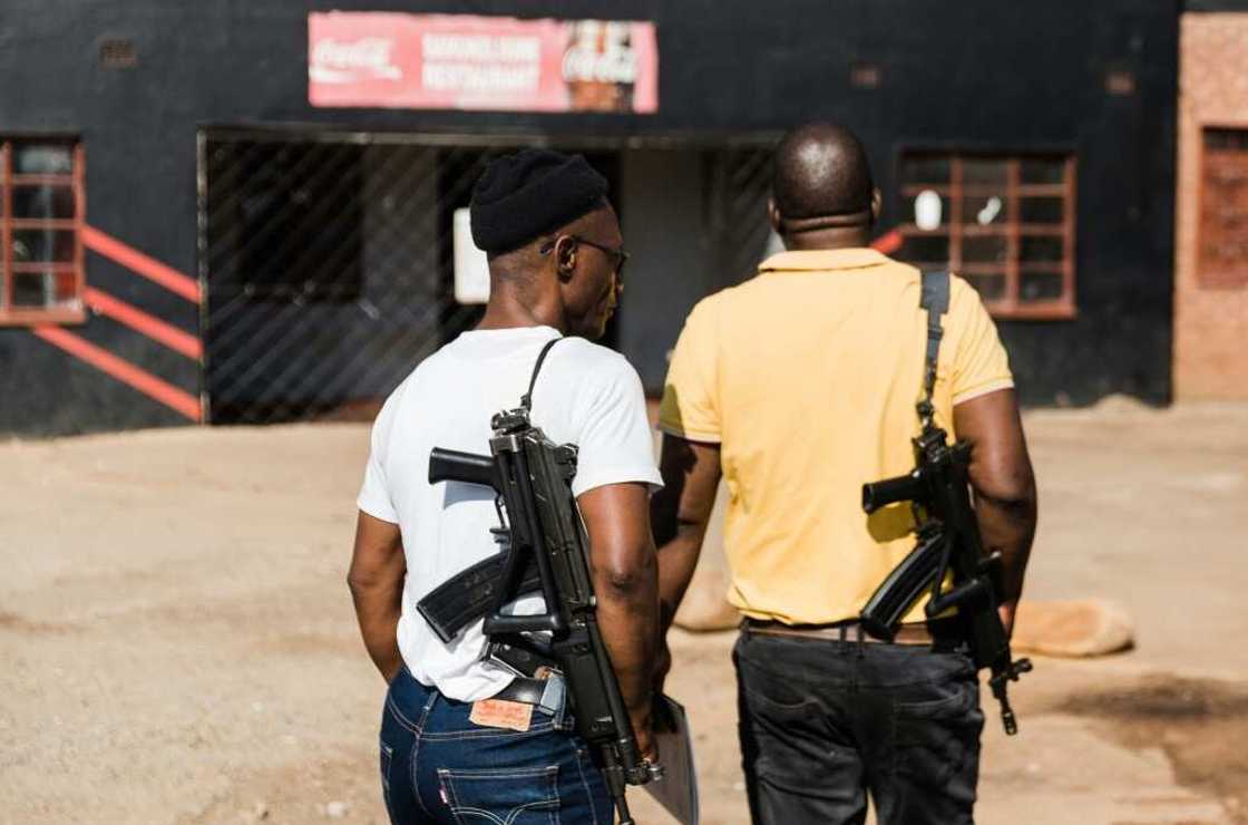 Security guards stand outside the scene of a shooting were four people died near Pietermaritzburg