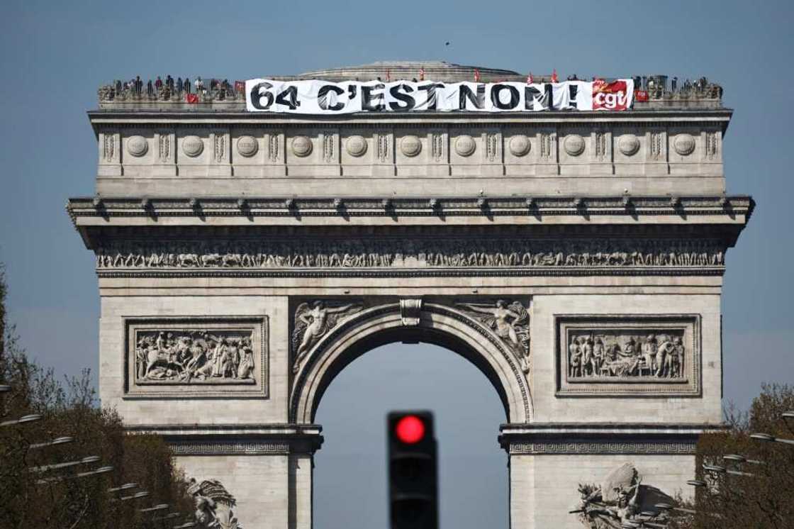 Activists unfurled a banner at the top of the capital's landmark Arc de Triomphe, reading 'No to 64' Activists unfurled a banner at the top of the capital's landmark Arc de Triomphe, reading 'No to 64'