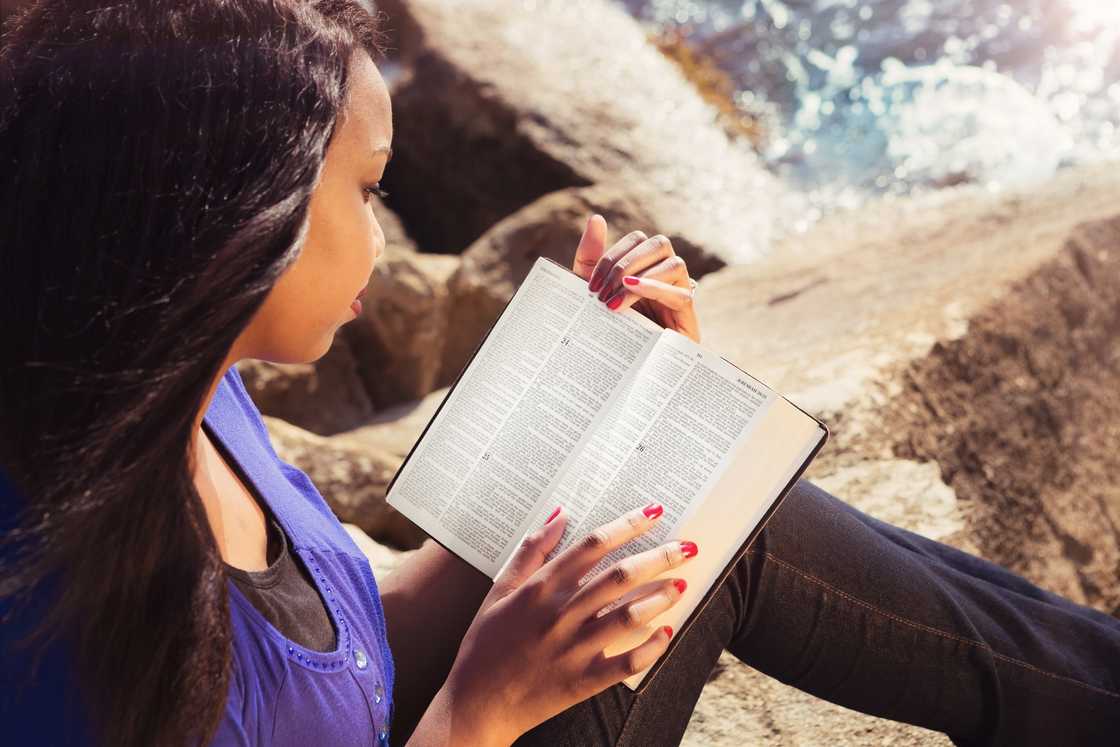 Young girl studying her bible outdoors Young girl studying her bible outdoors