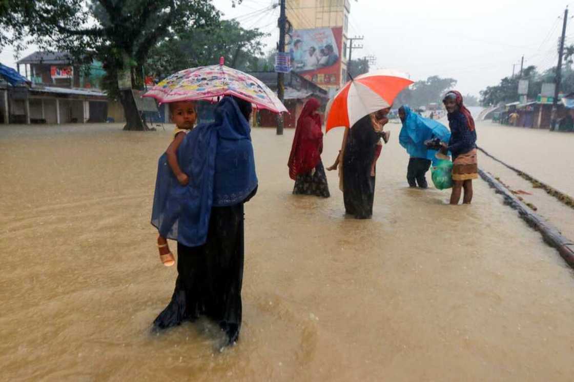 People wade along a flooded road following heavy monsoon rains in Sylhet, Bangladesh People wade along a flooded road following heavy monsoon rains in Sylhet, Bangladesh