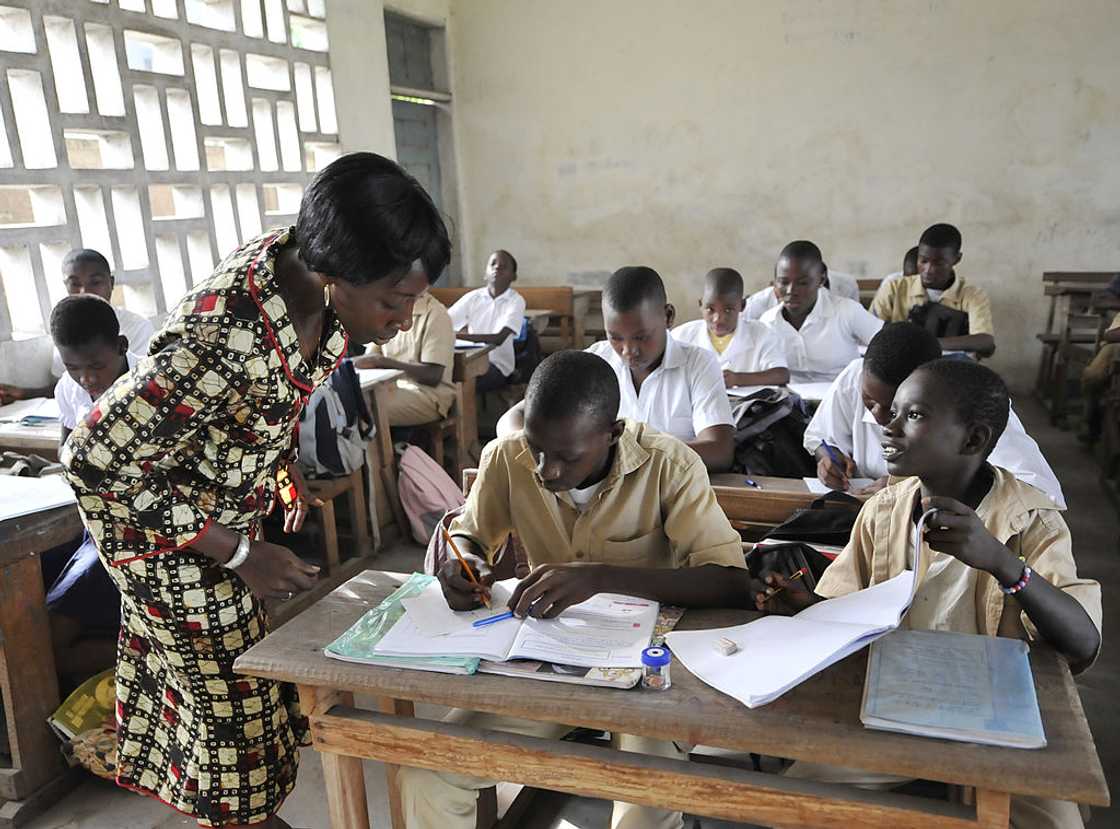 Female teacher attending to students in class. Female teacher attending to students in class.
