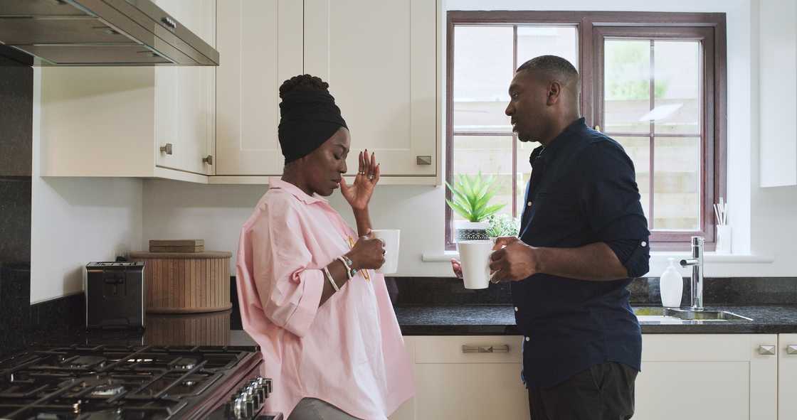 A black couple argue in a kitchen.