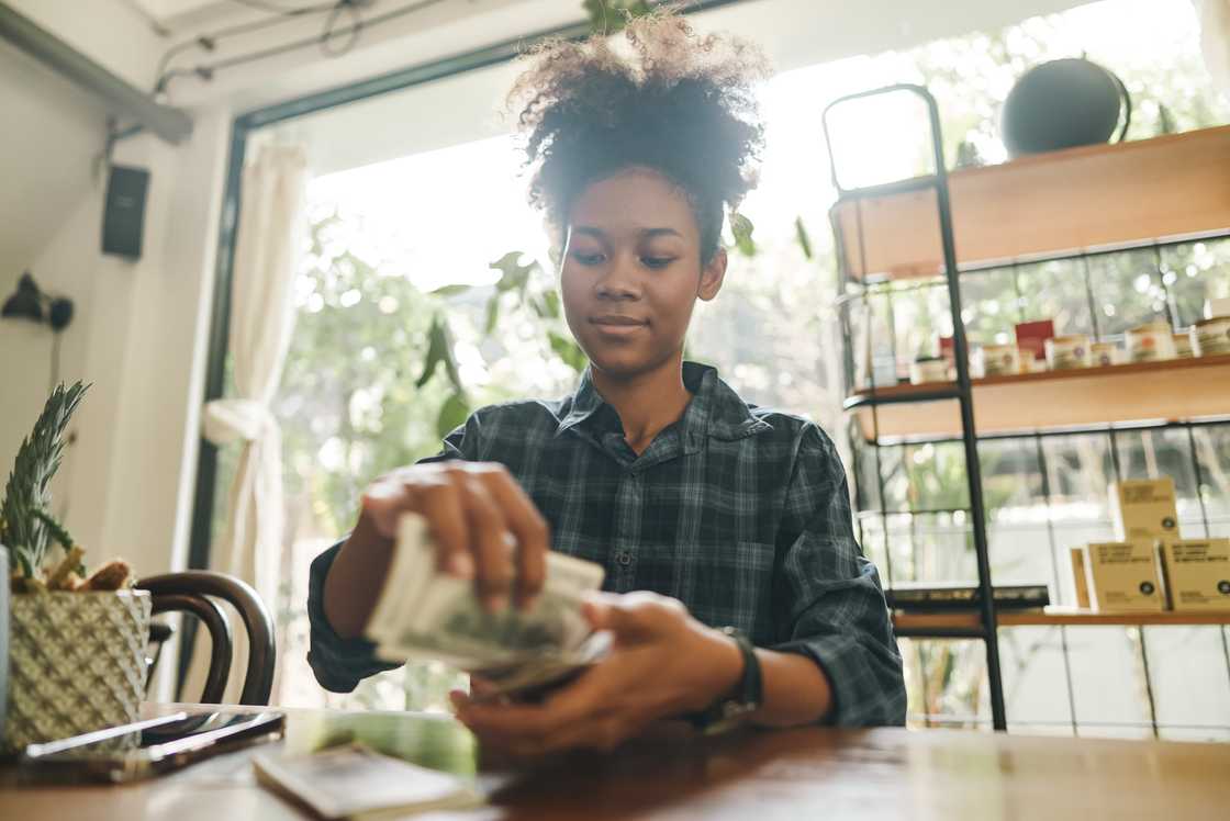 Owner of small business cafe counting dollars bills by hand. Owner of small business cafe counting dollars bills by hand.
