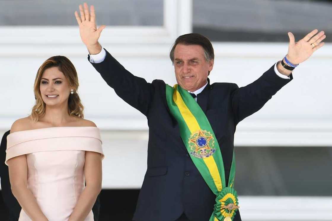 In January 2019, Brazil's new president Jair Bolsonaro (R) waves to supporters next to his wife Michelle after receiveing the presidential sash from outgoing president Michel Temer at the presidential palace in Brasilia