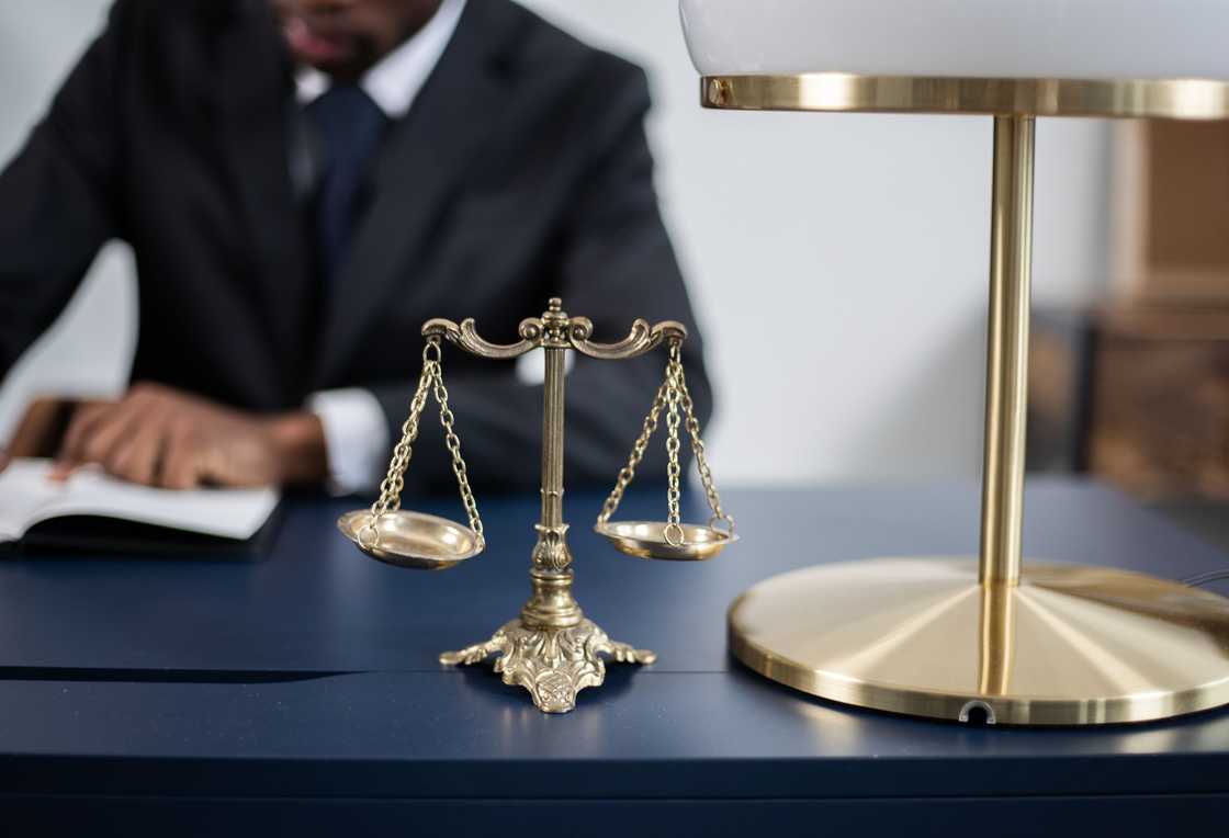 A wooden gavel on top of a law book alongside golden scales of justice. A wooden gavel on top of a law book alongside golden scales of justice.