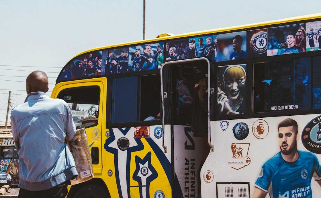 A man stands beside a decorated bus on a street.