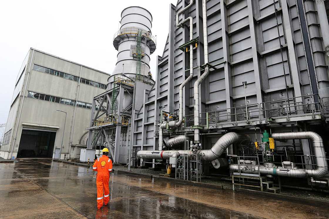 A worker wearing Royal Dutch Shell Plc branded overalls walks through the grounds Shell Petroleum Development Company of Nigeria