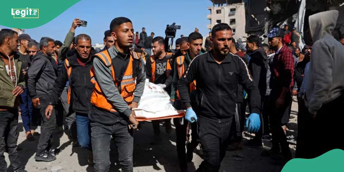 Rescuers carry the body of a victim amid the debris of Sheikh Radwan police station.