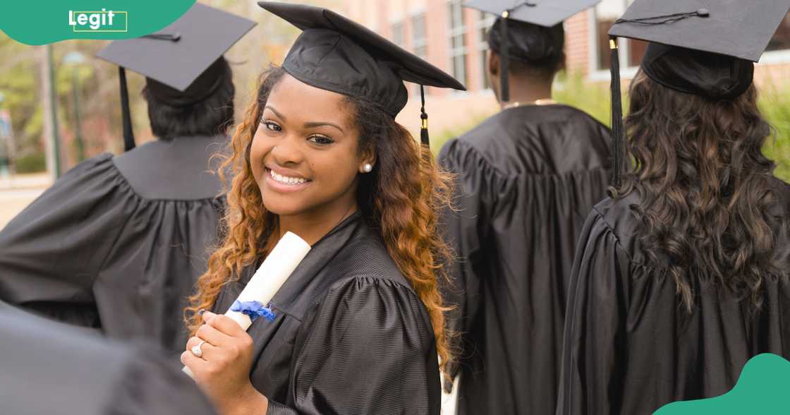 A student looks back for a photo in a black graduation gown.