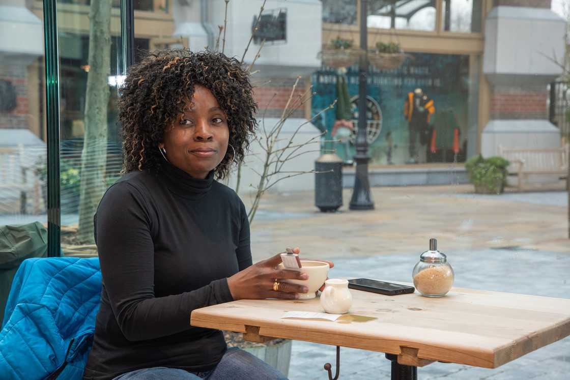 A woman with a cup of tea watching the street.