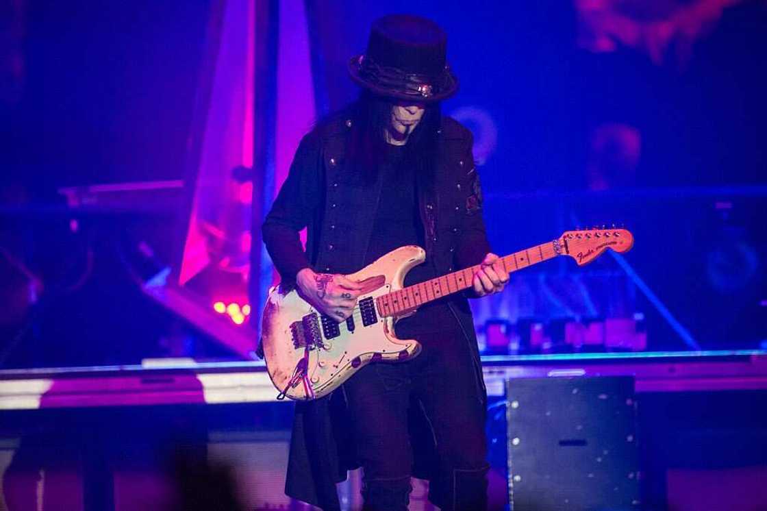 Mick Mars of Motley Crue playing guitar on stage in a black outfit