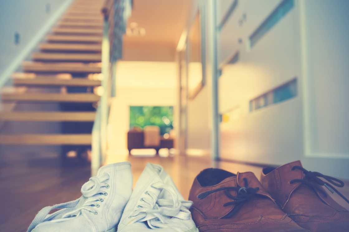Two pairs of shoes by a staircase in a modern home.
