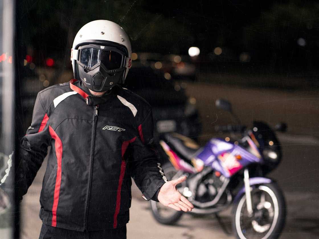 Motorbike rider wearing helmet and mask beside parked bike. Motorbike rider wearing helmet and mask beside parked bike.