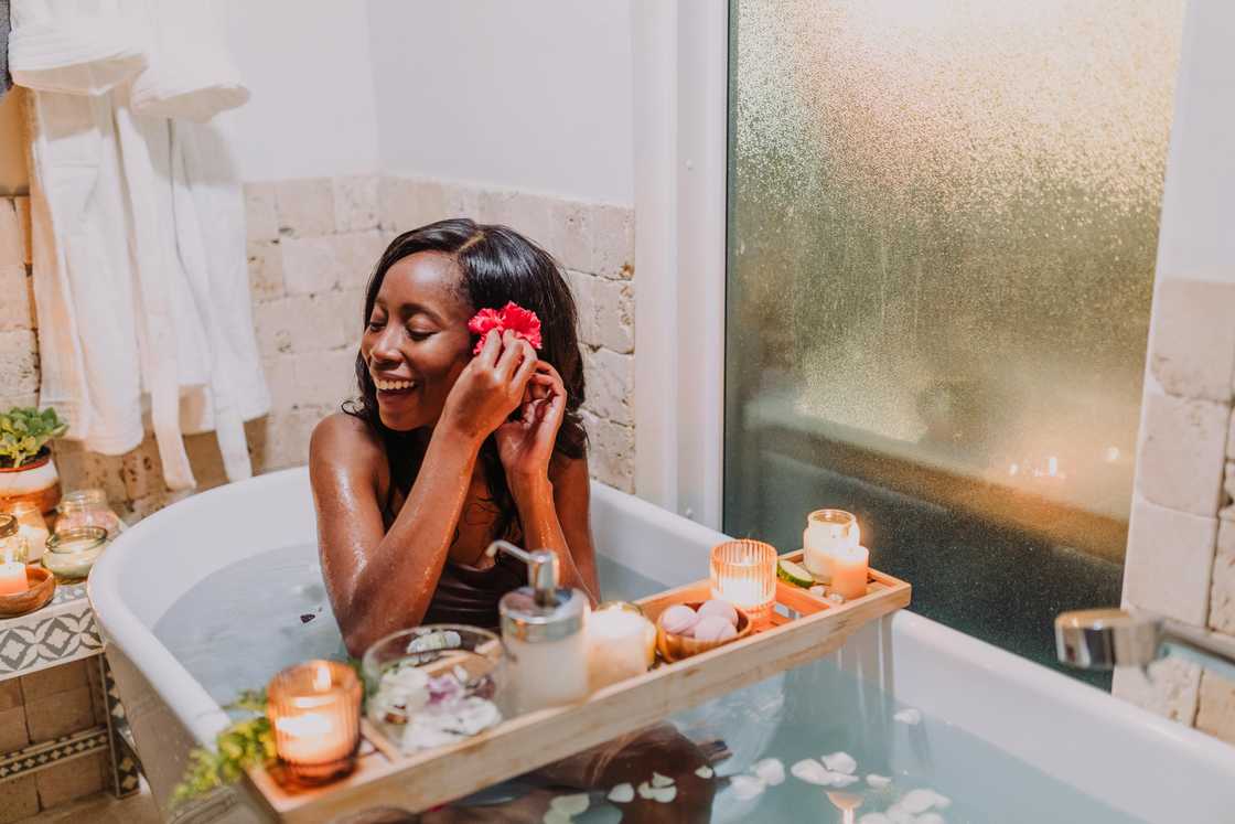 A woman in a bathtub putting a red flower behind her ear A woman in a bathtub putting a red flower behind her ear