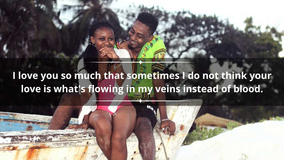 A happy young couple in colourful outfits is siting on an old boat