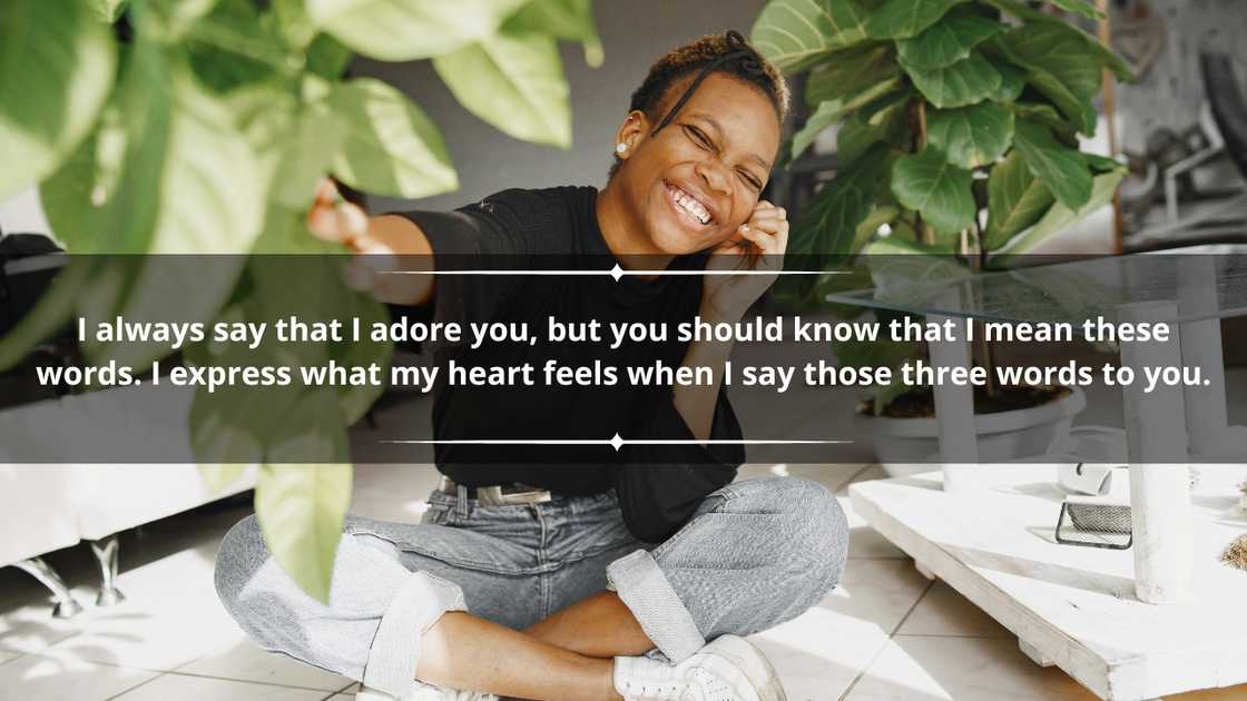 A happy woman in denim pants and a black top touching a plant