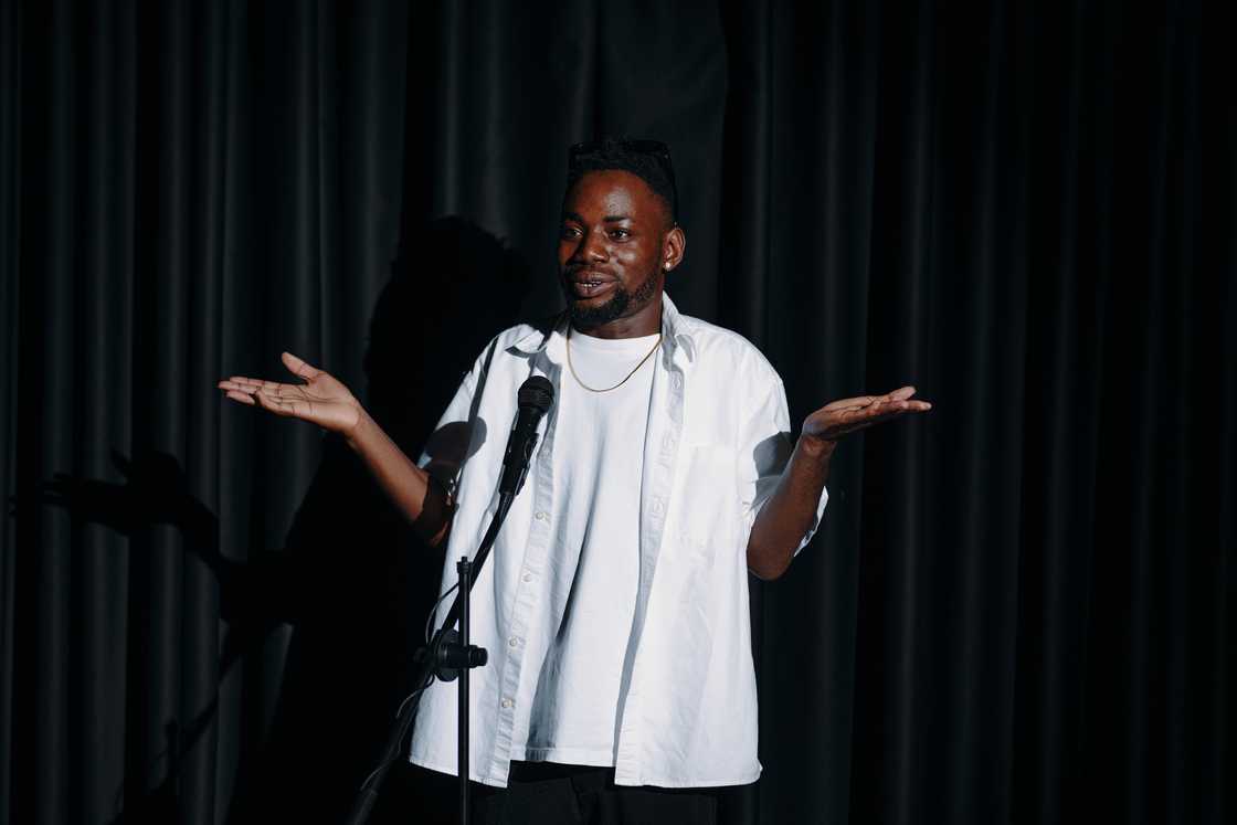 A man wearing a casual white shirt, performing a stand-up comedy. A man wearing a casual white shirt, performing a stand-up comedy.