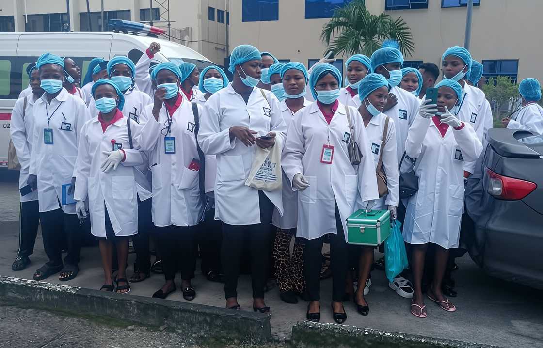 Students in white coats and protective gear pictured standing.