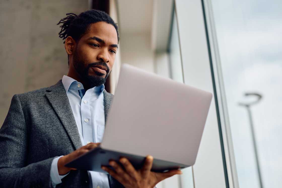 A man using a laptop while standing A man using a laptop while standing
