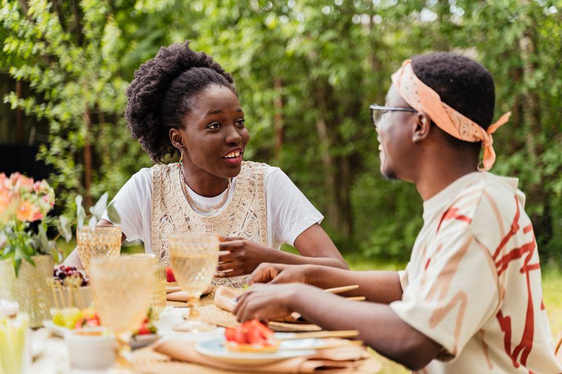 A woman talks animatedly with a man as they share a meal outdoors. A woman talks animatedly with a man as they share a meal outdoors.
