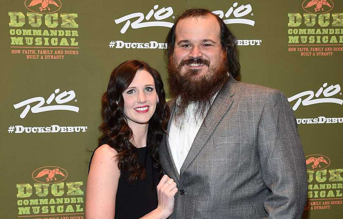 Brittany Brugman in a black dress and Justin Martin in a white shirt and grey coat pose for a photo