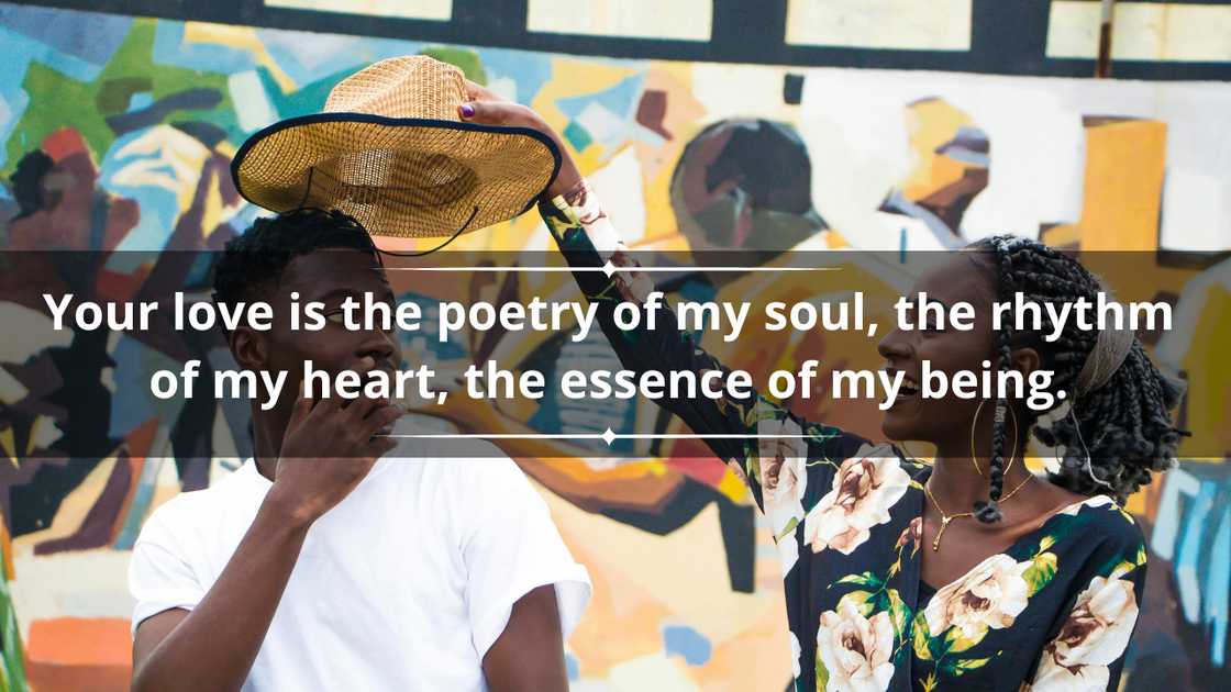 A happy woman in a flowery dress is holding a hat over a man in a white tee A happy woman in a flowery dress is holding a hat over a man in a white tee